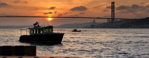 Istanbul Tours for Romantics: Sunset paints the Bosphorus in fiery hues, as lovers hand-in-hand watch sailboats dance on the shimmering waves.